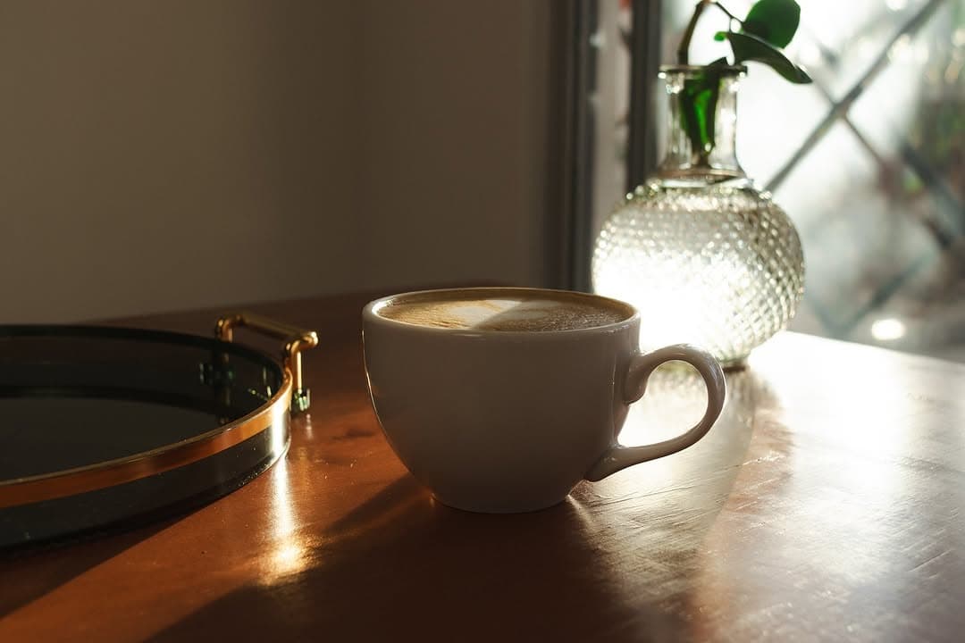 Taza de café con leche y arte latte sobre mesa de madera